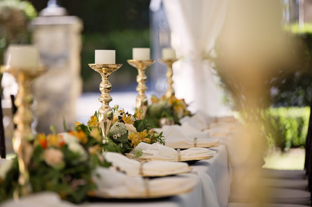 Luxurious outdoor wedding table setting with flowers and candlesticks.